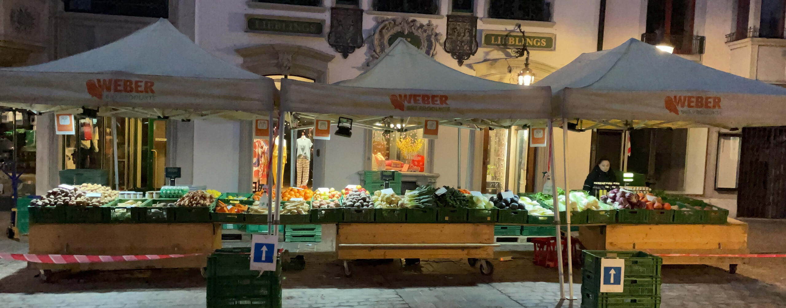 Gemüsestand auf einem nächtlichen Markt unter drei Weber-Pavillons